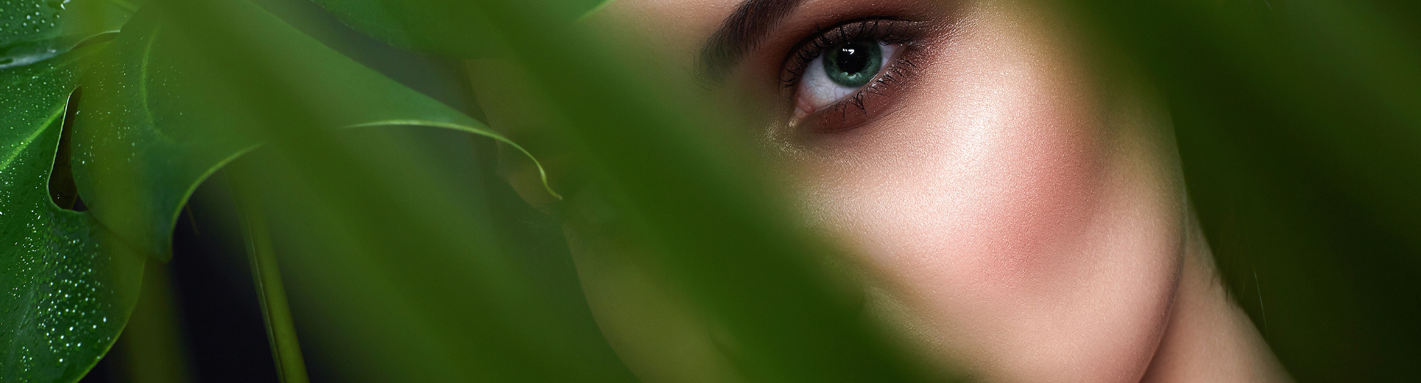 Woman peering through foliage.
