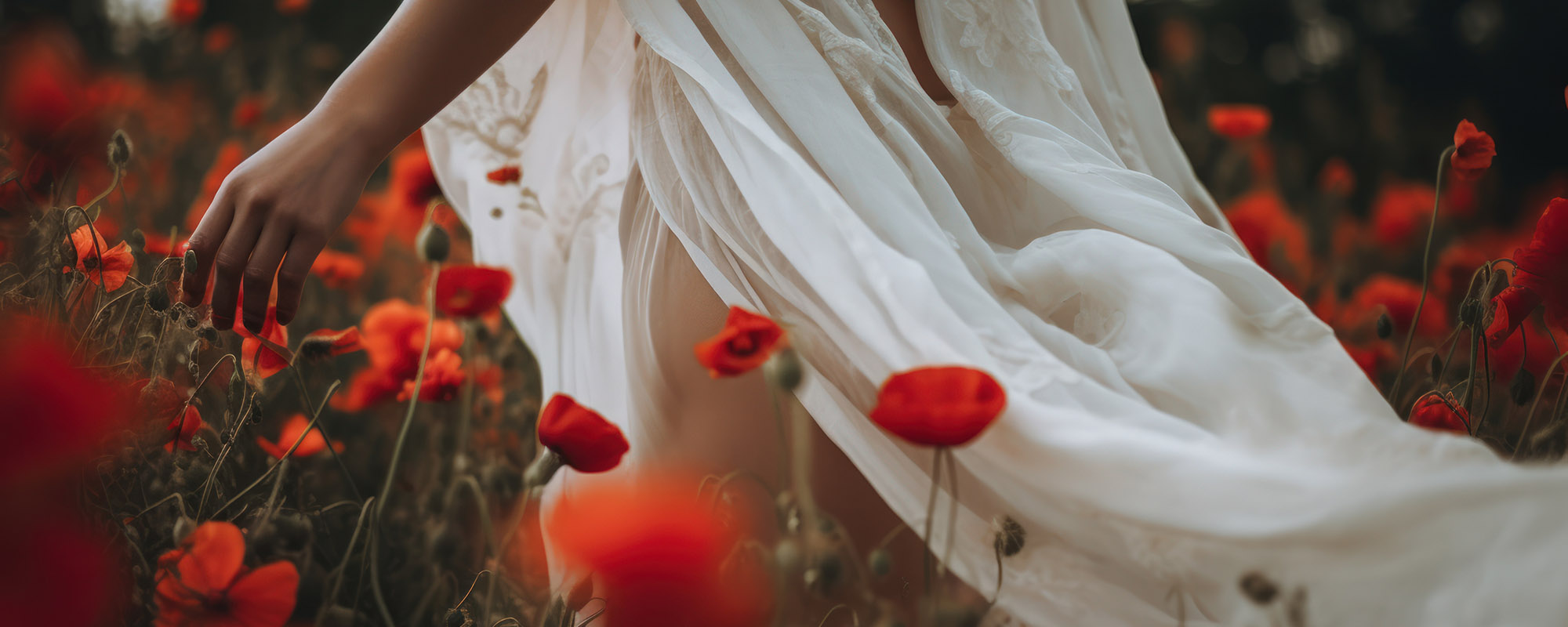 Woman in white dress walking in a field of poppies.